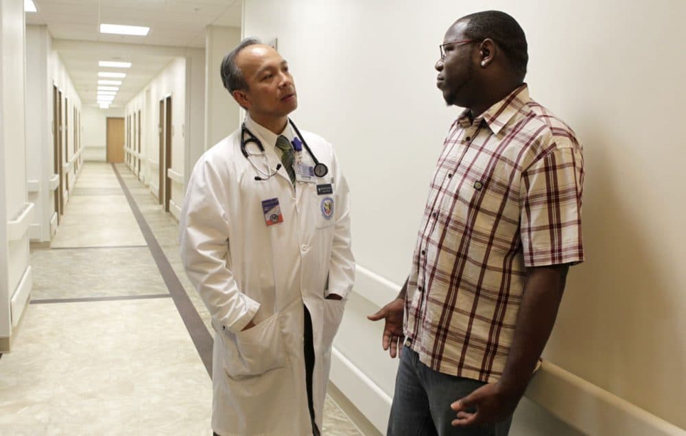 Dr. Dzung Le, D.O. talks with retired Air Force Staff Sgt. Shalum Scott in the hallway after his appointment at the Department of Veteran's Affairs Clinic in Fort Worth, Texas in 2010. (Sharon Ellman/AP)