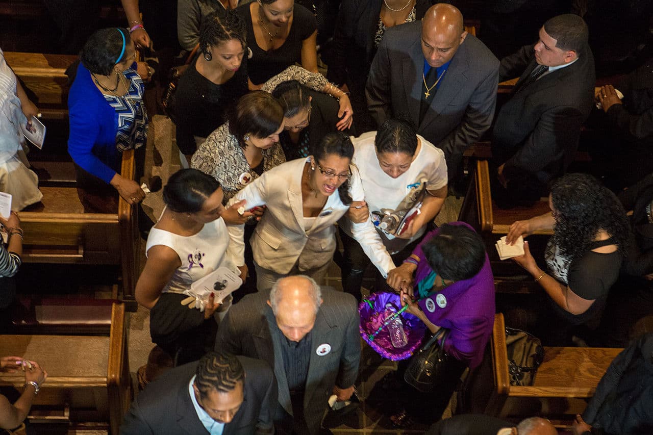 Friends and relatives comfort Laura Fatima Dos Santos as her son's casket is ushered out of St. Peter’s Parish Church. (Jesse Costa/WBUR)
