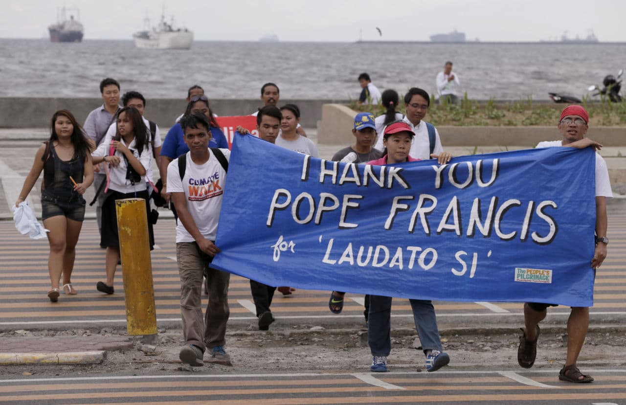 Environmental activists carry a banner as they march towards a Roman Catholic church to coincide with Pope Francis' encyclical on climate change in Manila, Philippines. In a 190-page document released Thursday, Francis describes ongoing human damage to nature. (Bullit Marquez/AP)