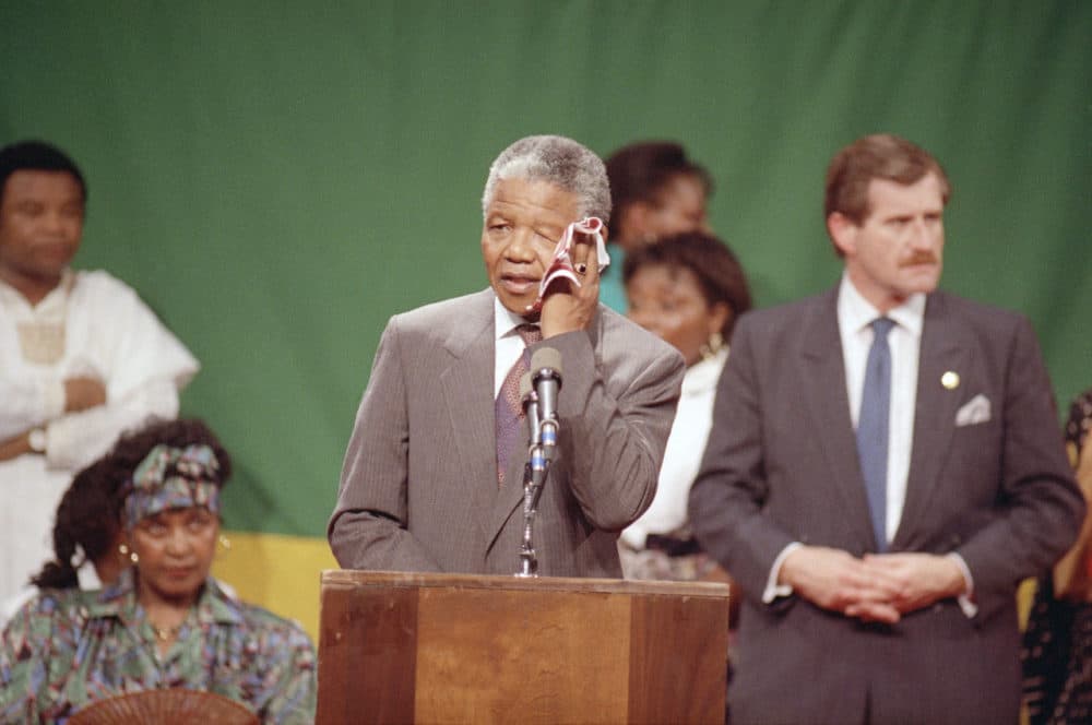 Nelson Mandela wipes his brow in the hot, humid gymnasium of the Madison Park High School in the Roxbury section of Boston 25 years ago. An exhuberant crowd packed the gymnasium for Mandela's appearance. (Jim Gerberich/AP)