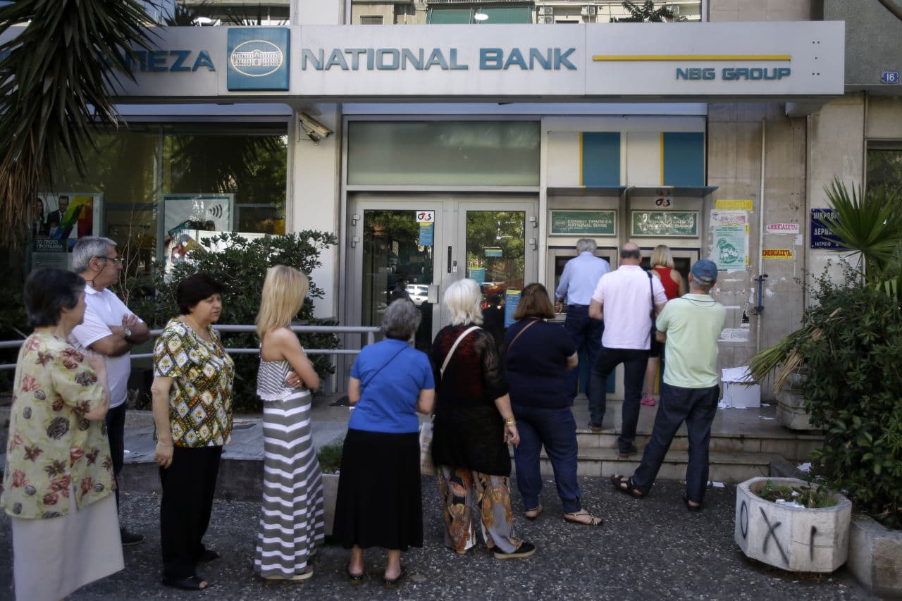 People stand in a queue to use an ATM outside a closed bank, next to a sign on the plant, bottom right, reading ''NO'' in Athens, Tuesday. It's crunch time for Greece, with the European part of its international bailout expiring Tuesday. (Thanassis Stavrakis/AP)