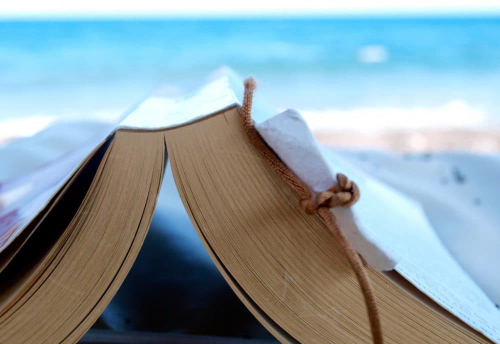 Reading a book at the beach. (simon_cocks/Flickr)