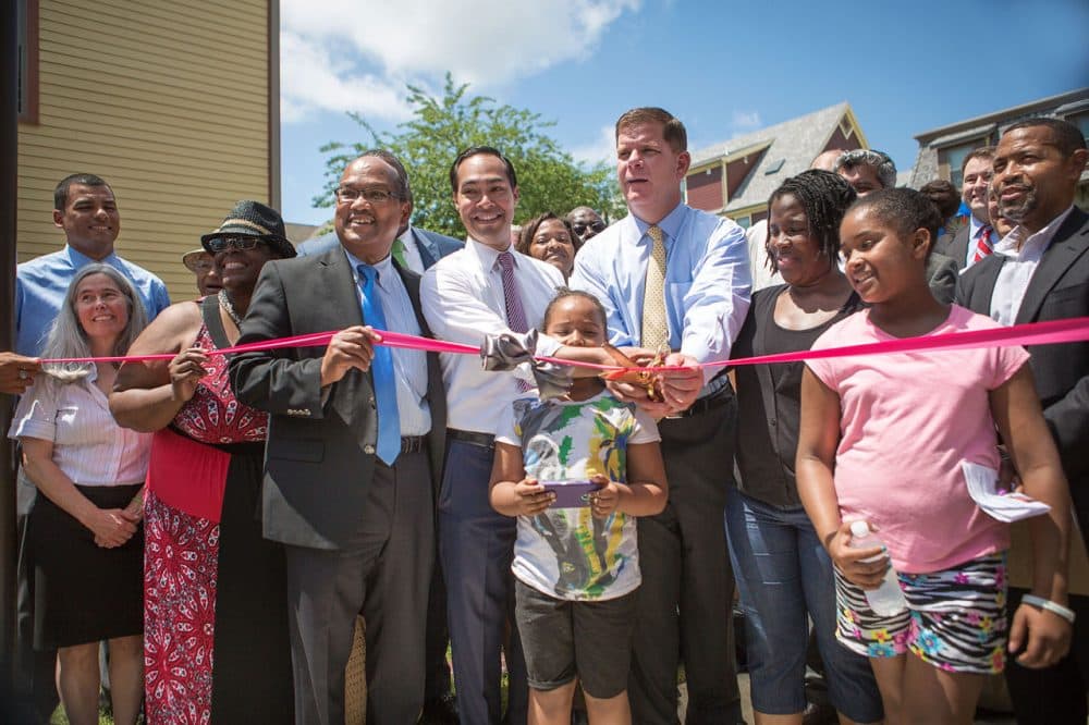 Mayor Marty Walsh, U.S. Housing Secretary Julián Castro, City Councilor Charles Yancey and members of the community prepare to cut the ribbon during a ceremony at the new Quincy Heights housing development in Dorchester Tuesday. The new development is also home to a 35,000-square-foot shared food production facility. (Jesse Costa/WBUR)