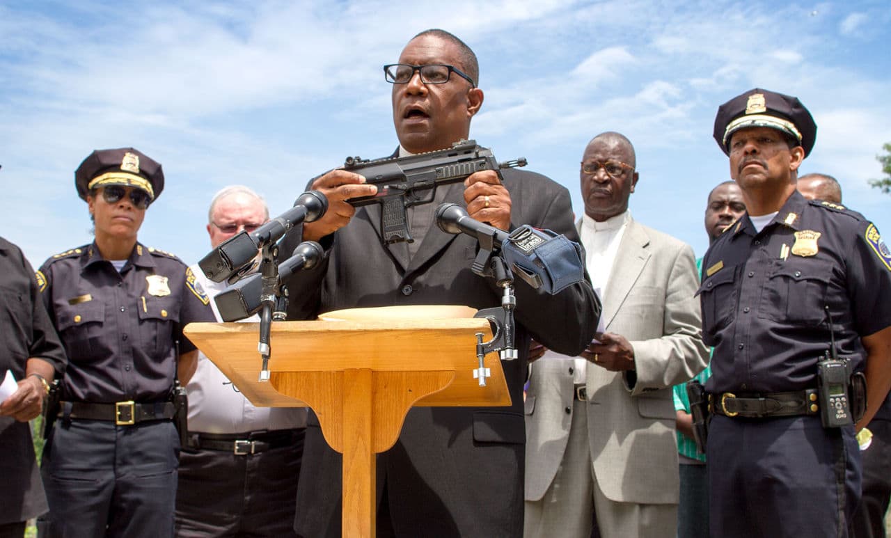 Surrounded by police and other clergy, the Rev. Mark Scott speaks at a gathering of Boston faith leaders calling attention to the potential dangers of toy or replica firearms. (Hadley Green for WBUR)