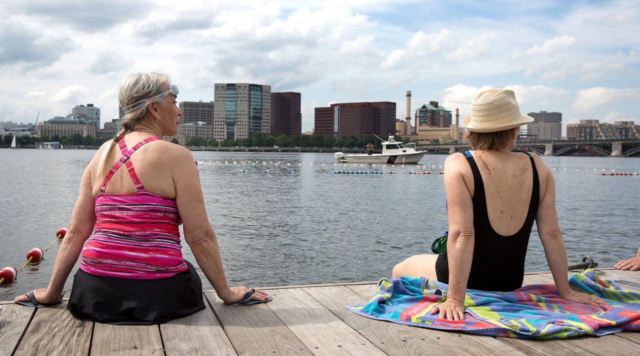 Beverly Sky, 67, and Karen Edlund, 65, sit on the Fiedler Dock by the Charles waiting for swimming to begin.  “I’ve always dreamed of jumping in the Charles,” says Beverly. (Robin Lubbock/WBUR)