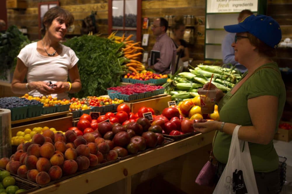 A vendor at the Stillman's Farm stand talks with a customer at the Boston Public Market. (Hadley Green for WBUR)