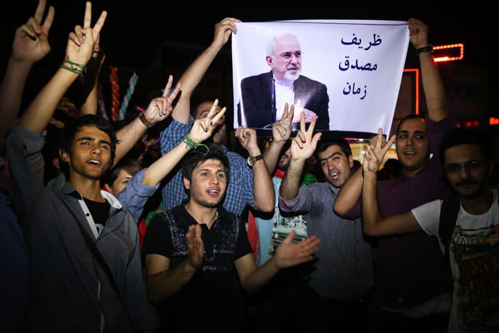 Young Iranian men cheer and show victory sign with a picture of Foreign Minister Mohammad Javad Zarif, reading "Zarif is Mosaddegh of our time," comparing Zarif to Mohammad Mosaddegh, Iran's legendary prime minister during the 1950s who nationalized the country's oil industry, in Tehran, Iran, Tuesday, July 14, 2015. (AP)