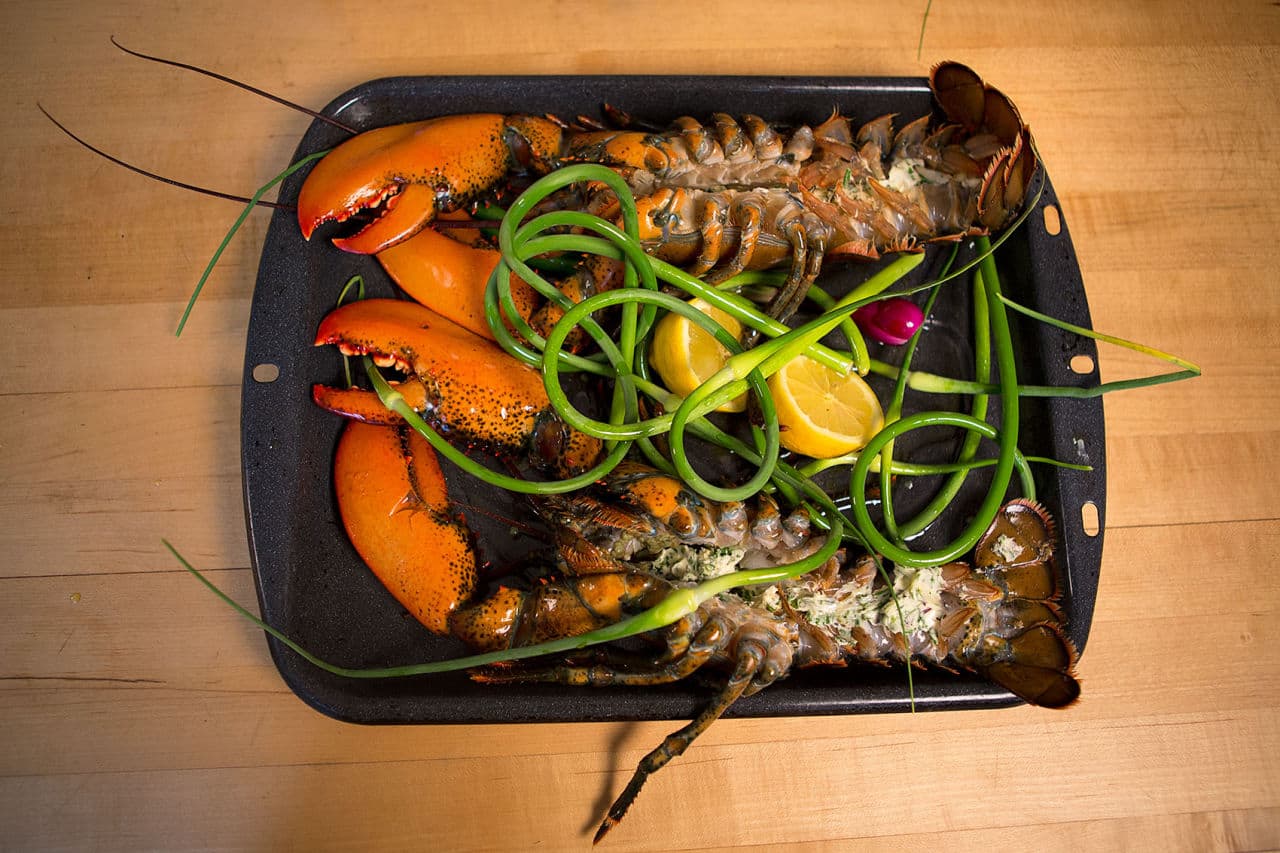 A pair of lobsters with garlic scapes and lemon are ready to be grilled. (Jesse Costa/WBUR)
