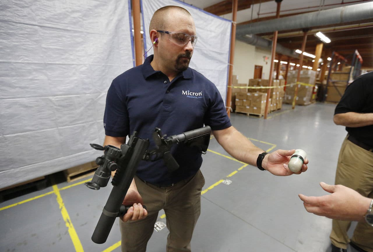 Chad Zrate, of Fitchburg, Mass., an engineering manager at Micron Products, Inc., in handed a 40mm Blunt Impact Projectile, or PIB, as he prepares to demonstrate firing the cartridge in a launcher at the company&#039;s manufacturing plant. (Steven Senne/AP)