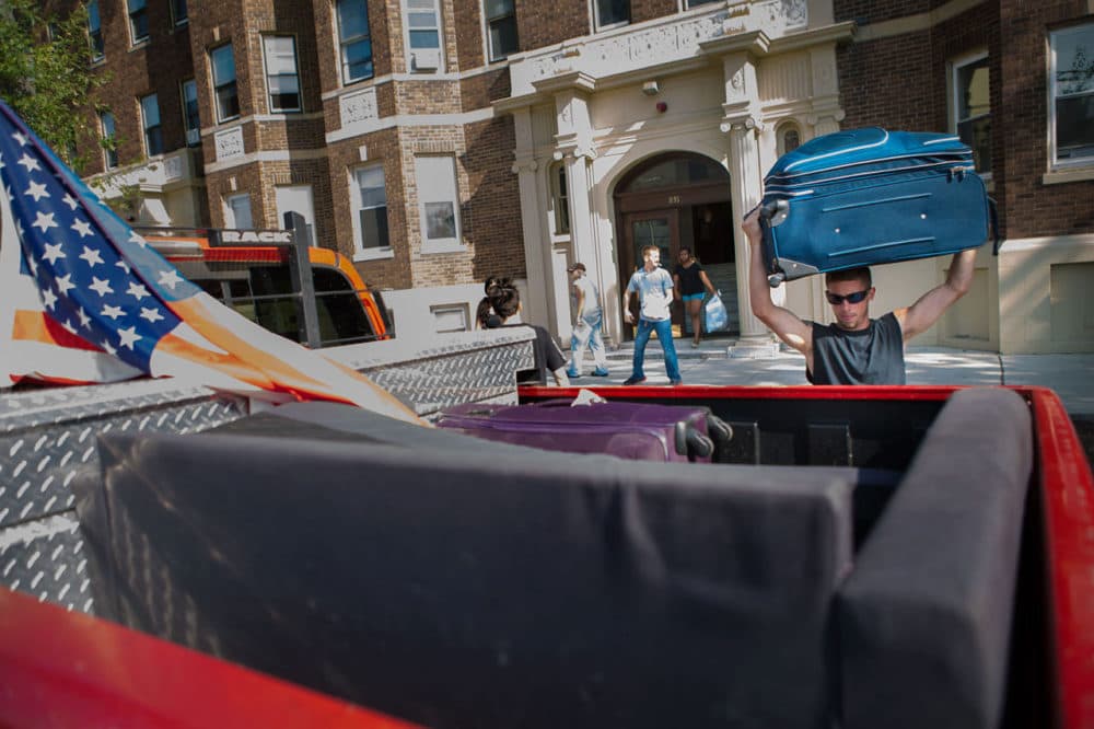 On Monday, Kevin Weldon, a Boston University senior, lifts a suitcase into his pickup truck while helping friends relocate from Comm. Ave. to another apartment in Allston. (Jesse Costa/WBUR)