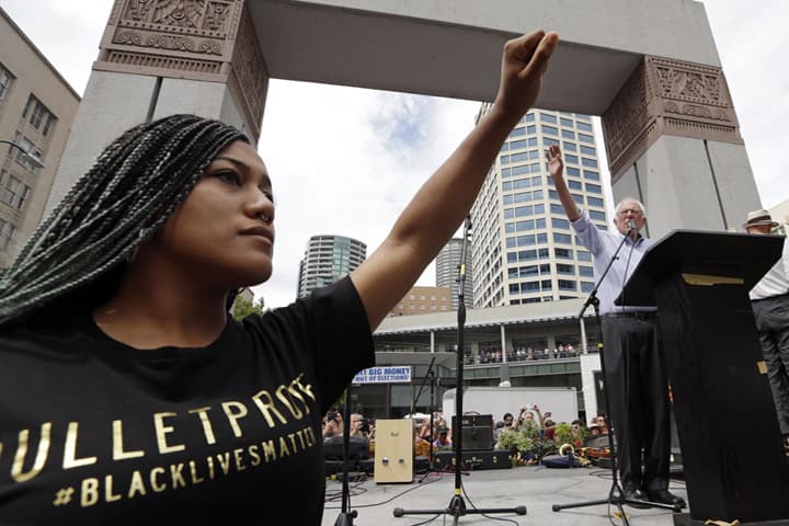 Mara Jacqueline Willaford, left, holds her fist overhead as Democratic presidential candidate Sen. Bernie Sanders, I-Vt., waves to greet the crowd before speaking at a rally Saturday, Aug. 8, 2015, in downtown Seattle.  (AP)