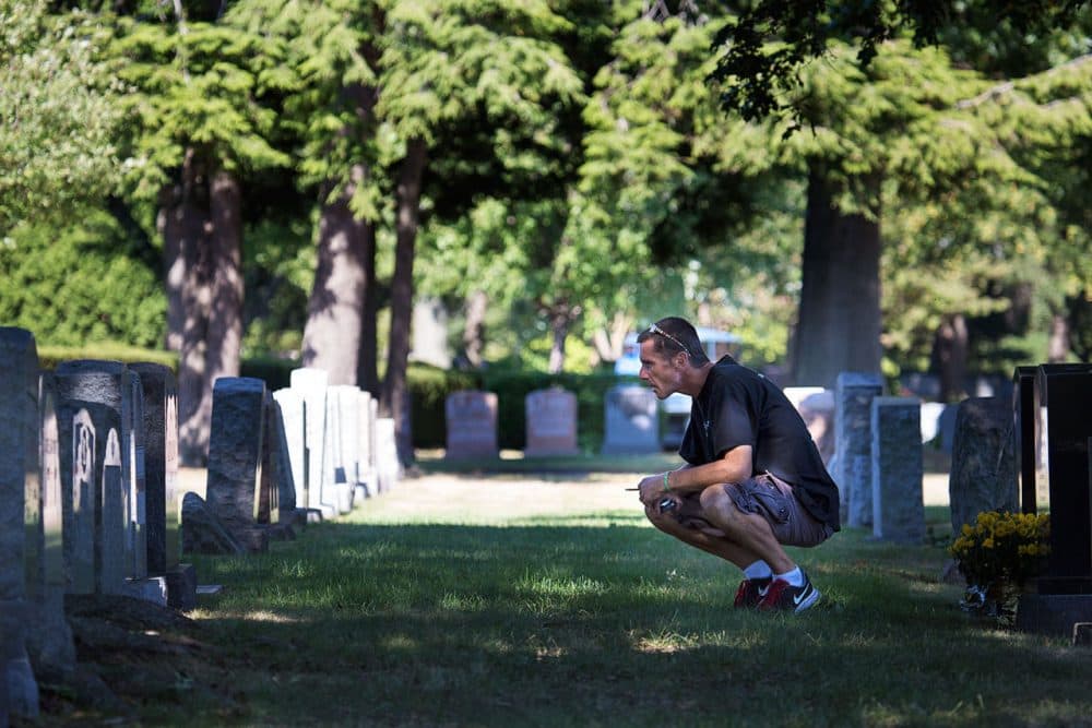 In this 2015 photo, Joey, who had recently started using methadone to try and kick his heroin addiction, visits his parents grave at Woodlawn Cemetery in Everett. (Jesse Costa/WBUR)