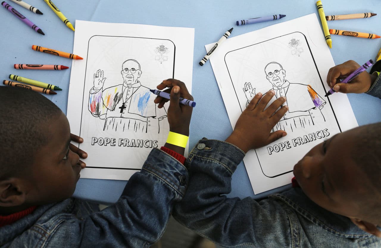 Kaydn Dorsey, 4, left, and Lionel Perkins, 4, draw on a coloring sheet bearing the image of Pope Francis as they wait for him to arrive on a visit to Catholic Charities of the Archdiocese of Washington, Thursday, Sept. 24, 2015. The charity serves dinner to about 300 homeless people daily at the site. (David Goldman/AP)
