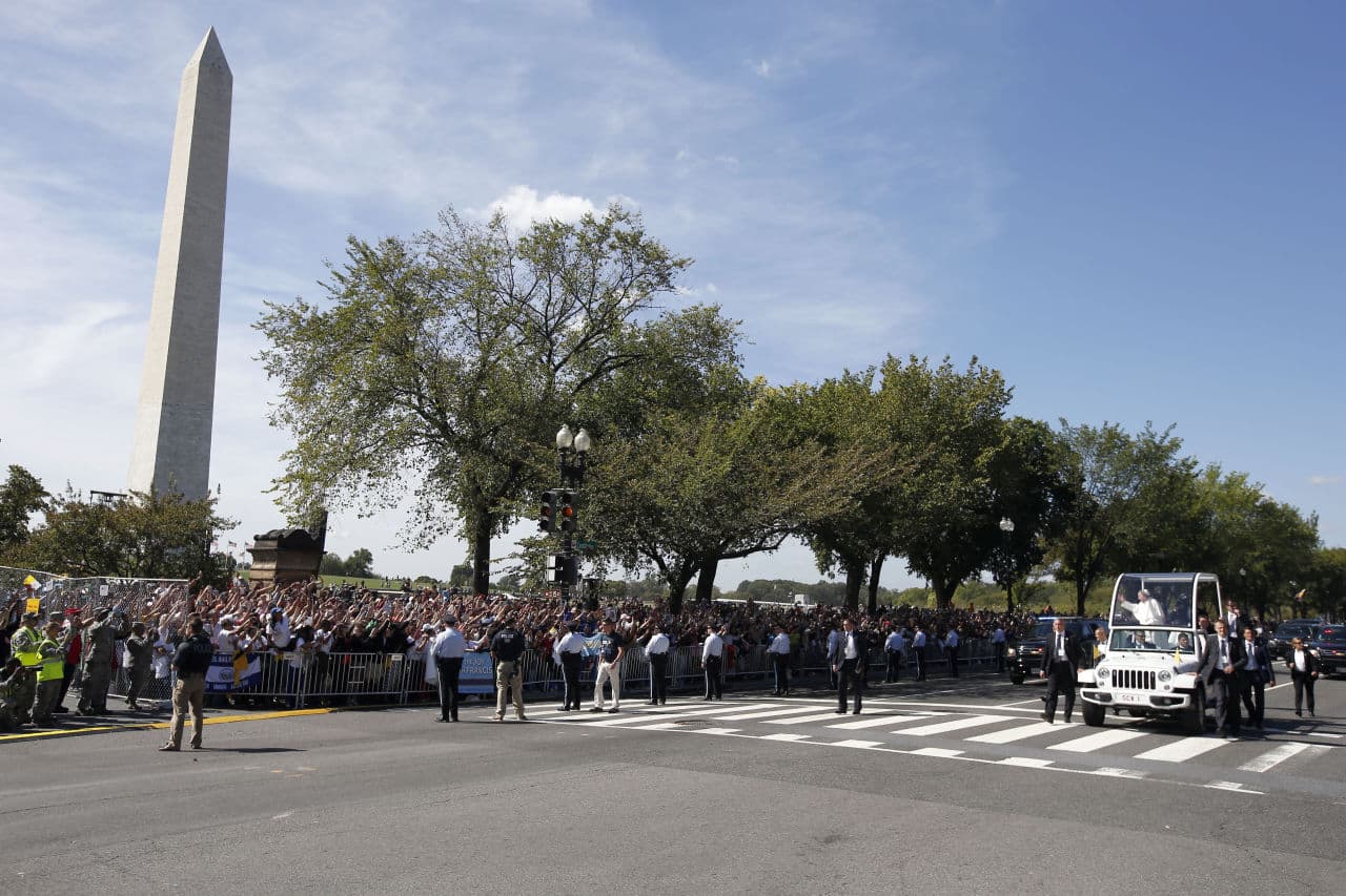 With the Washington Monument on the left, Pope Francis waves to the masses from the popemobile during a parade on Constitution Avenue Wednesday. (Alex Brandon/AP)