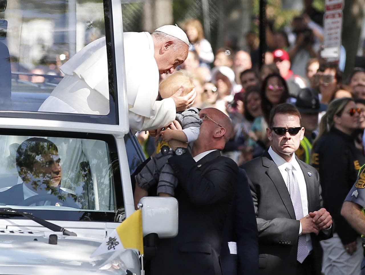 Pope Francis holds the head of a small child as he leans from the popemobile during a parade. (Alex Brandon/AP)