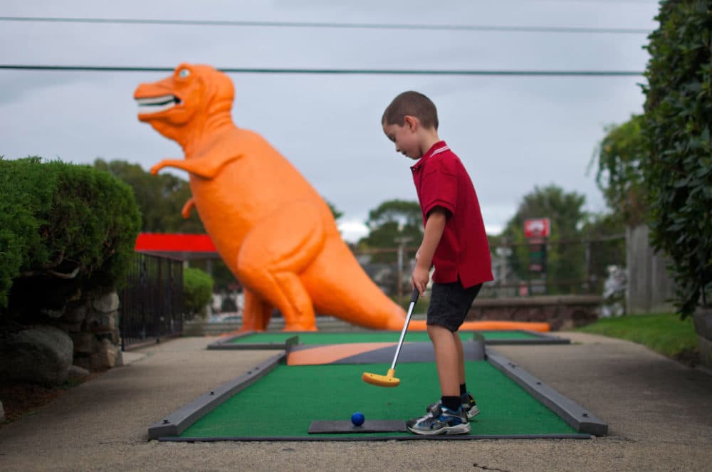 After more than 50 years, the old-fashioned miniature golf course off Route 1 in Saugus is closing. The spot is well known for its dayglo orange T-rex that, from the sixth hole, gazes over the highway. Here, Louie Schraffa, 5, of East Boston, prepares for a putt on the dinosaur hole. (Sharon Brody/WBUR)