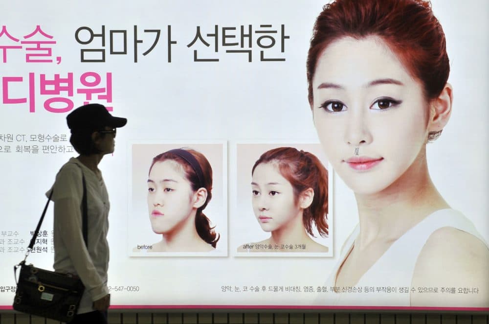This picture taken on May 22, 2013 shows a South Korean woman walking past a street billboard advertising double-jaw surgery at a subway station in Seoul. South Korea's obsession with plastic surgery is moving on from standard eye and nose jobs to embrace a radical surgical procedure that requires months of often painful recovery. (Jung Yeon-Je/AFP/Getty Images)