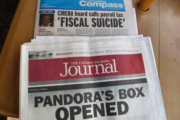 In this Aug. 2, 2012 file photo, local newspapers show stories about the controversial strategy to bail the government out of a financial hole, at a restaurant along Seven Mile Beach on the outskirts of George Town on the Cayman Islands. The Cayman Islands have lost some of their allure by abruptly proposing what amounts to an income tax on expatriate workers who have helped build the territory into one of the most famous or, for some people, notorious offshore banking centers that have tax advantages for foreign investment operations. (AP)