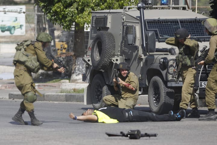 An Israeli soldier shoots and kills a Palestinian holding a knife after he stabbed another Israeli soldier, seen kneeling,, center, during clashes in Hebron, West Bank Friday, Oct. 16, 2015. (AP)