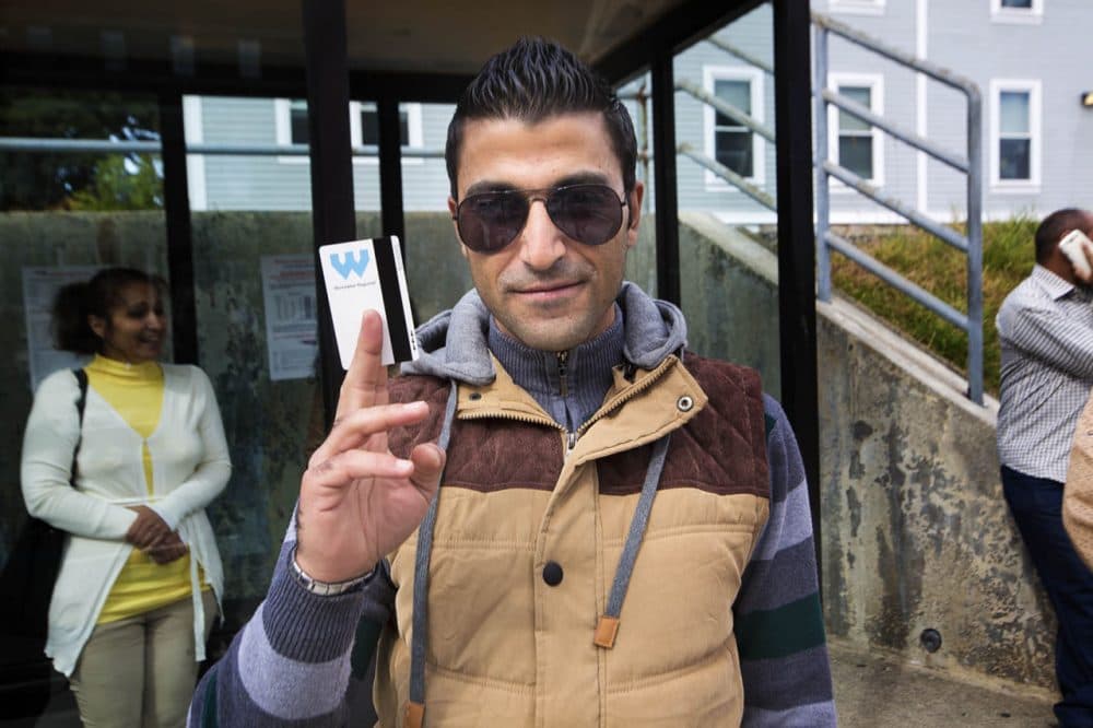 Mohammed Al Asmi, of Syria, holds a WRTA bus pass he received for an Ascentria class on how to navigate around Worcester by public transportation. (Jesse Costa/WBUR)