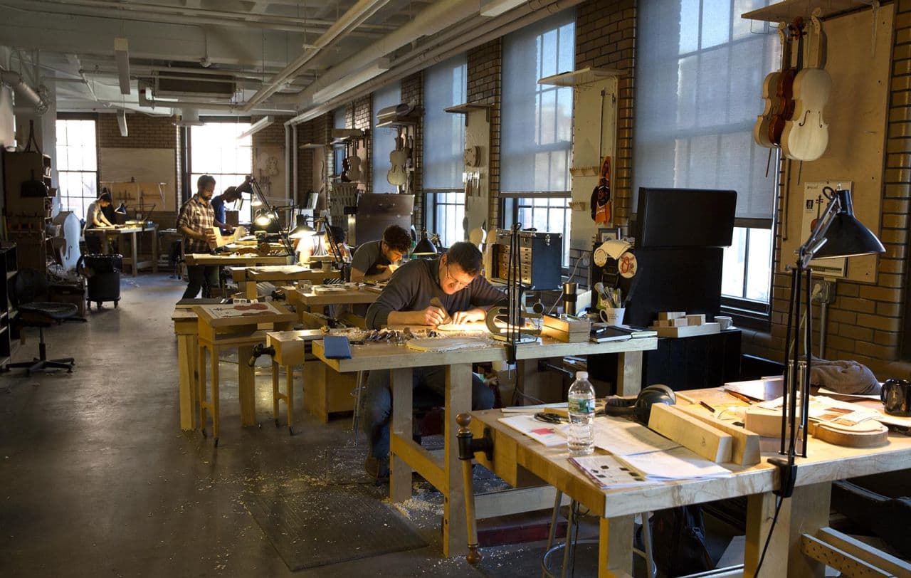 Brian Worley (right) works on the creation of a violin at the North Bennet Street School. (Robin Lubbock/WBUR)