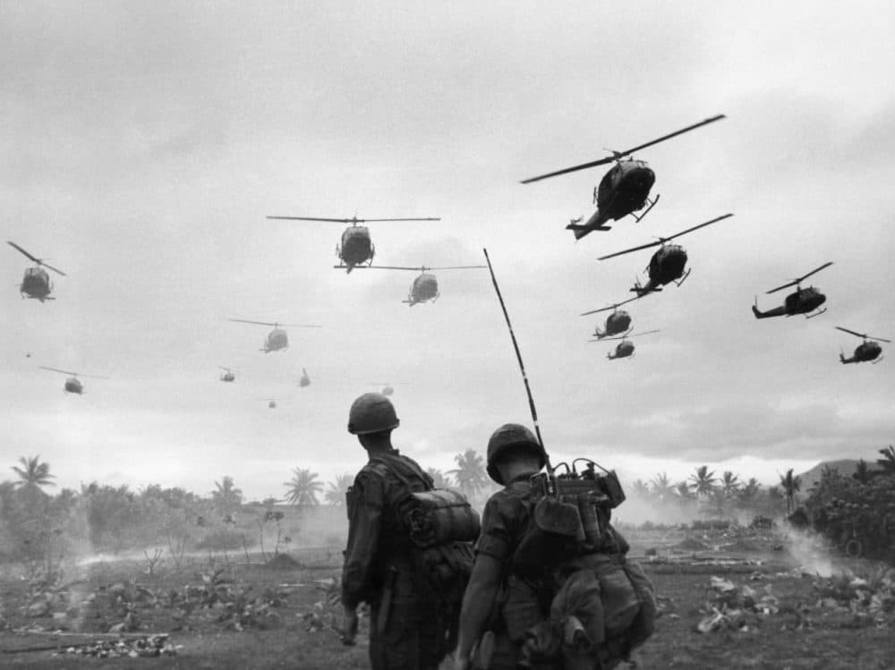 The second wave of combat helicopters of the 1st Air Cavalry Division fly over an RTO and his commander on an isolated landing zone during Operation Pershing, a search and destroy mission on the Bong Son Plain and An Lao Valley of South Vietnam, during the Vietnam War. The two American soldiers are waiting for the second wave to come in.  (Patrick Christain/Getty Images)