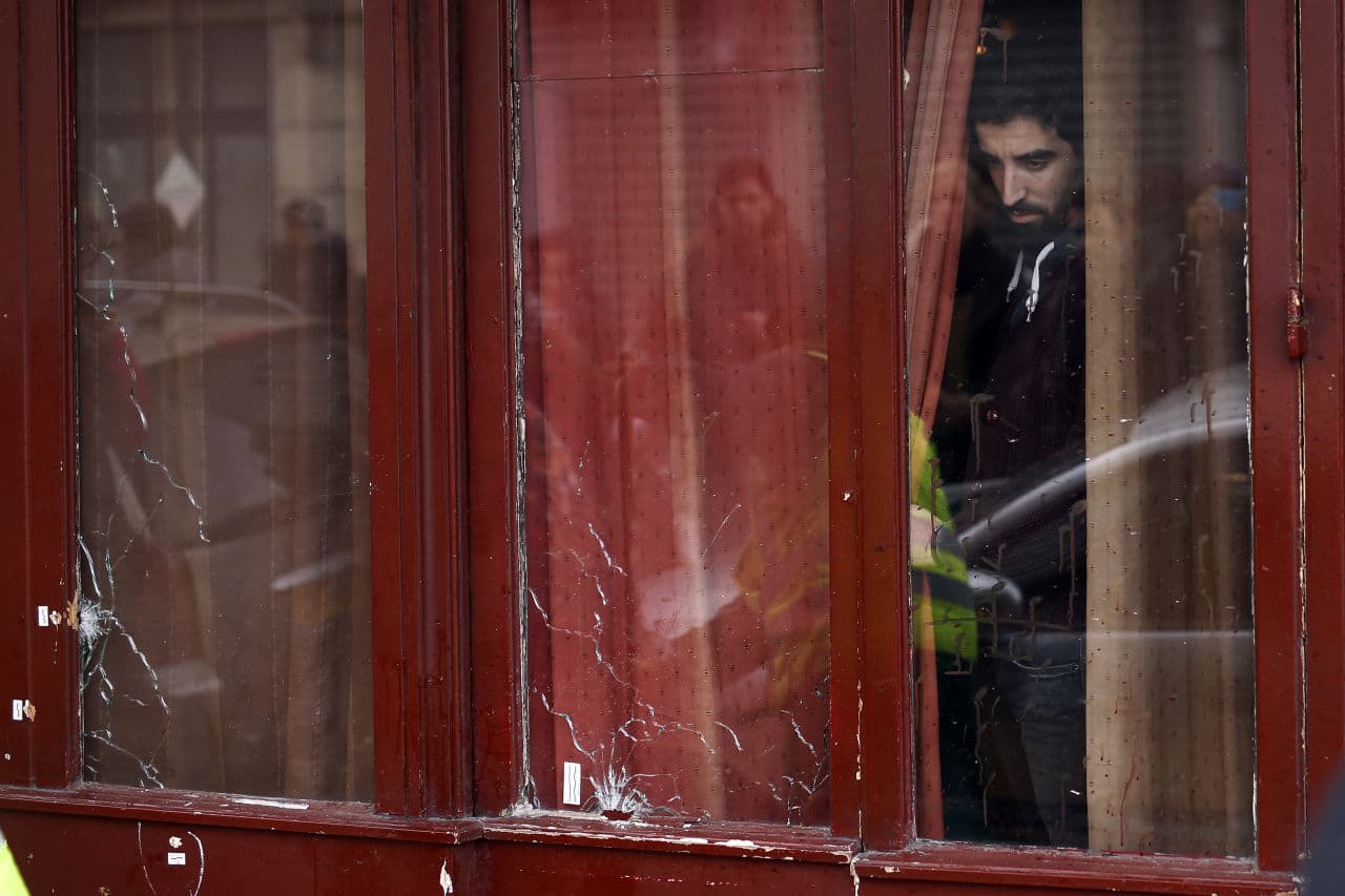 A man looks out the bullet ridden windows of the Carillon cafe in Paris on Saturday. (Jerome Delay/AP)