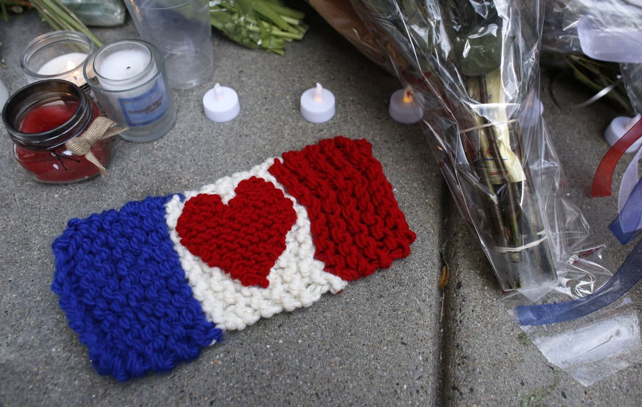 A knitted French flag with a heart design in the center rests on the sidewalk next to candles outside the French Consulate in Boston, Sunday, Nov. 15, 2015. (Steven Senne/AP)