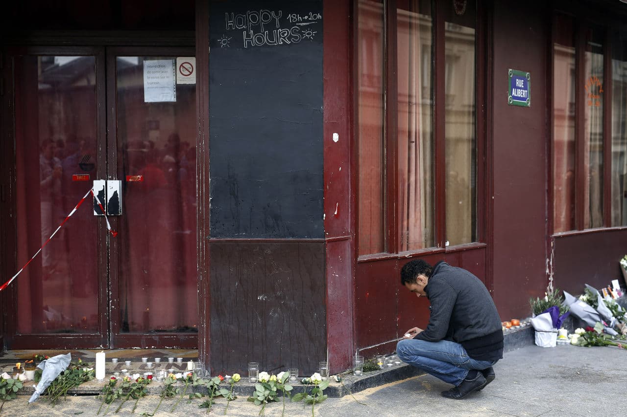 A man places a candle in front of the Carillon cafe in Paris, a day after over 120 people were killed in a series of shooting and explosions. (Jerome Delay/AP)