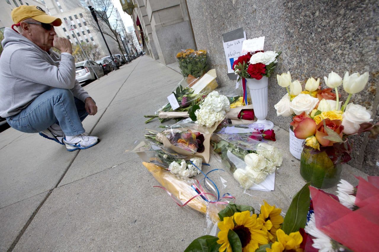 An unidentified man pauses after placing flowers on a make-shift memorial outside the French Consulate in Boston on Saturday, Nov. 14, 2015. (Michael Dwyer/AP)