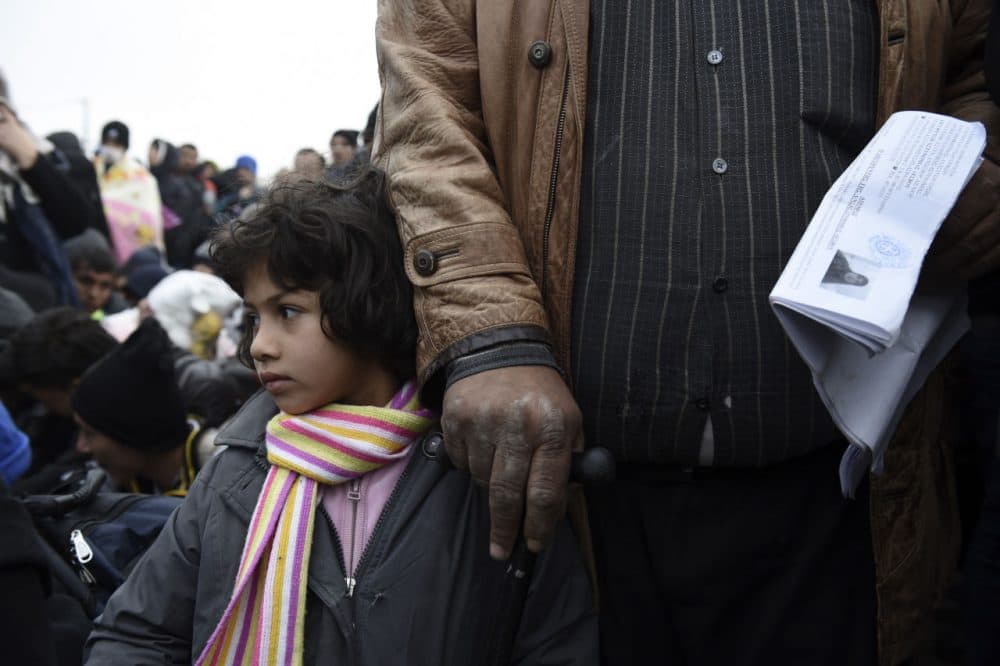 A Syrian girl with her father wait to be allowed by the Greek police to cross the borderline to Macedonia, near the village of Idomeni, Saturday, Nov. 21, 2015. Tempers have flared at Greece's main border crossing with Macedonia, where riot police pushed back thousands of migrants jostling to cross over, after Macedonia blocked access to people deemed to be economic migrants and not refugees. (AP Photo/Giannis Papanikos)