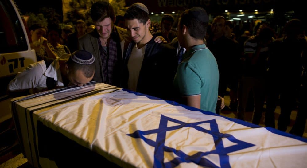 Friends of Ezra Schwartz, who was killed in a shooting attack in the West Bank that claimed two other lives, stand next to his coffin during a private ceremony at Ben Gurion Airport near Tel Aviv, Israel, Saturday, Nov. 21, 2015. Schwartz's body was repatriated to Boston for burial. (Oded Balilty/AP)