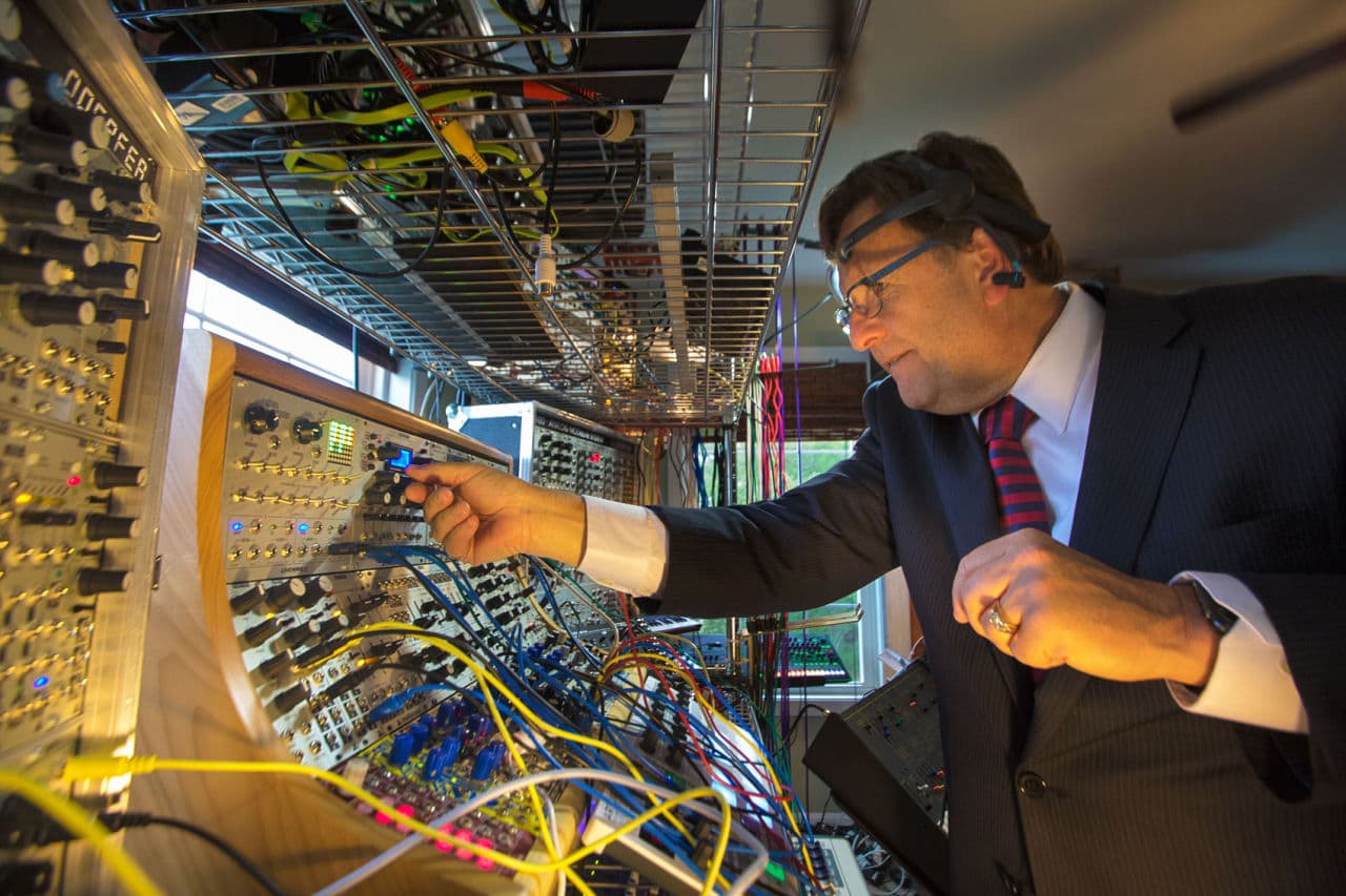 Dr. Richard Boulanger, a professor of electronic music and design at the Berklee College of Music, tweaks knobs and patches cables between audio synthesizers to create sounds using a brainwave reading device. (Jesse Costa/WBUR)