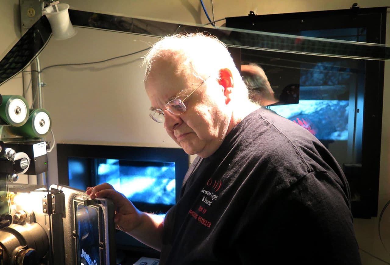 Boston Light &amp; Sound co-founder Larry Shaw takes a 70 mm projector for a test drive after installing it in a booth at a Providence multiplex. (Andrea Shea/WBUR) 