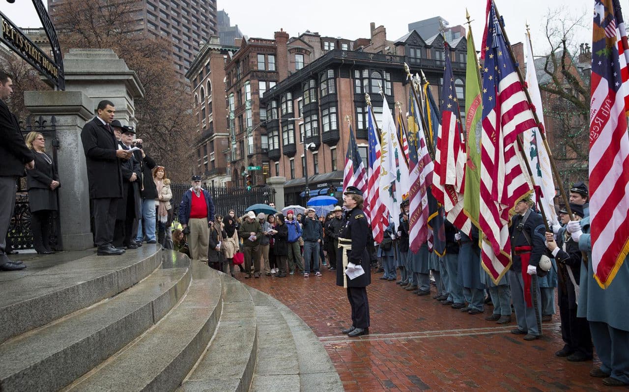 Secretary of Veterans' Services Francisco Urena welcomes flag bearers to the State House Tuesday to commemorate 150 years since the return of the state's Civil War battle flags. (Robin Lubbock/WBUR)
