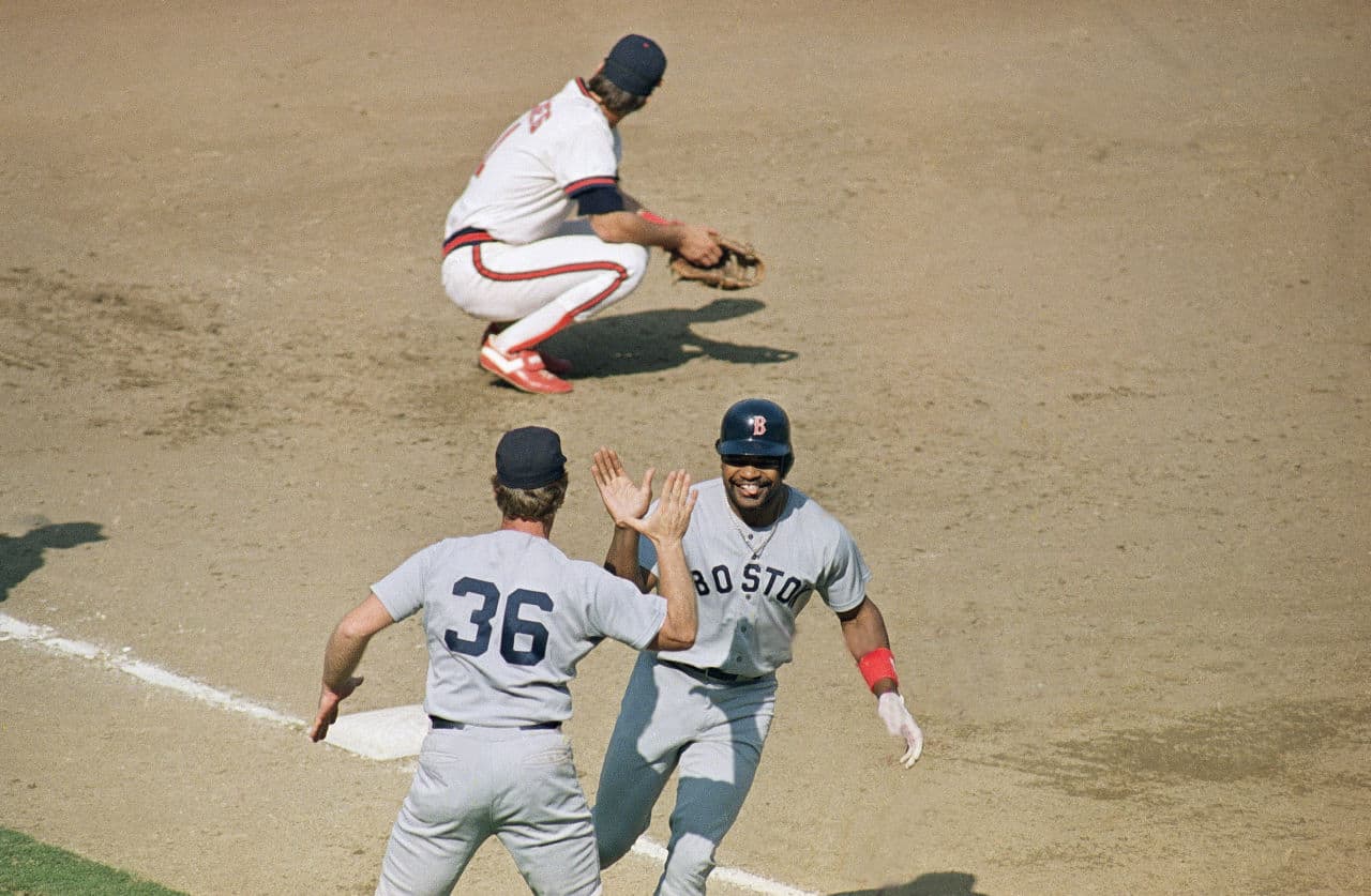 In this file photo, Dave Henderson playing for the Red Sox gives a high-five to coach Rene Lachemann as he rounds third. The Los Angeles Angels' Doug DeCinces can only watch after a ninth-inning homer to put the Sox ahead on Oct. 13, 1986. (Lennox McLendon/AP)