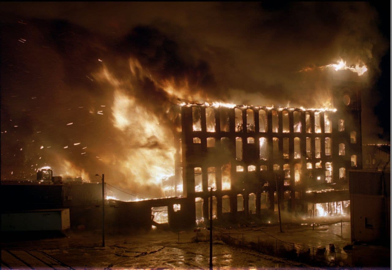 Flaming cinders shoot from one of four mill buildings putting nearby homes in danger as a multi-alarm fire rages at the Malden Mills textile complex in Methuen, Mass. Monday night, Dec. 11, 1995. Thirty-one workers have been reported injured in the fire and explosion, eight critically, with no confirmed deaths. (AP Photo/John Cetrino)