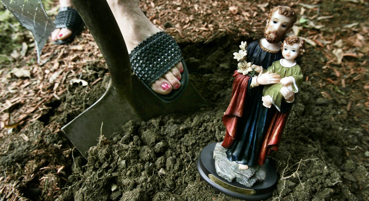 Home seller Diana Grammont of Lexington, Mass., gets ready to dig a hole in her front yard to bury a statue of St. Joseph. The belief that St. Joseph helps homeowners sell their homes traces back to St. Theresa of Avalon, a nun in the 17th century who buried a coin of the saint and prayed to him for help in getting land for monasteries. When the ritual worked, the practice spread. (Elise Amendola/AP)