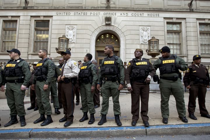 Sheriff officers stand guard in front of the courthouse main entrance as demonstrators protest outside of the courthouse after a mistrial of Officer William Porter, one of six Baltimore city police officers charged in connection to the death of Freddie Gray, on Wednesday, Dec. 16, 2015, in Baltimore. (AP Photo/Jose Luis Magana)