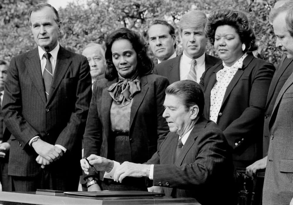 Former President Ronald Reagan signs the bill making Martin Luther King Jr.'s birthday into a national holiday, as Coretta Scott King watches on Nov. 2, 1983, in Washington. (Barry Thumma/AP)