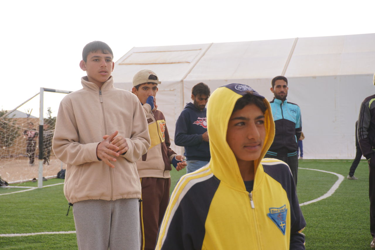 Hassan Ahmad (in yellow sweatshirt) is pictured on the Mercy Corps football field at Zaatari refugee camp. (Dale Gavlak)
