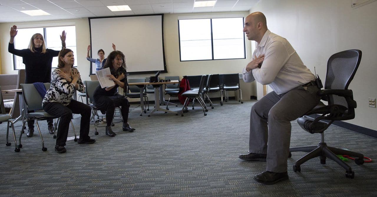 Fitness expert Rick DiScipio shows WBUR staff a sit and stand routine. (Robin Lubbock/WBUR)