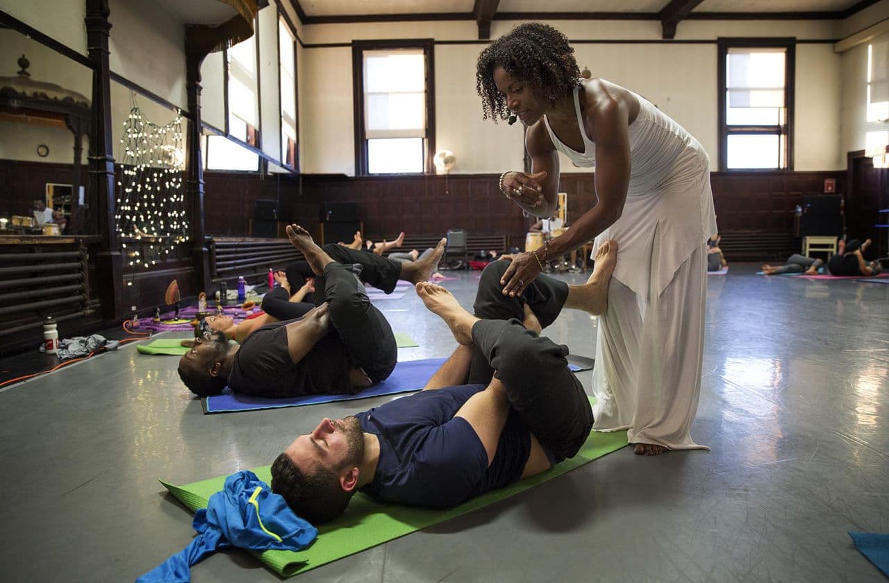 Afro Flow Yoga instructor Leslie Salmon Jones, assists Jesse Lyons, 32, at the Dance Complex in Cambridge. (Robin Lubbock/WBUR)