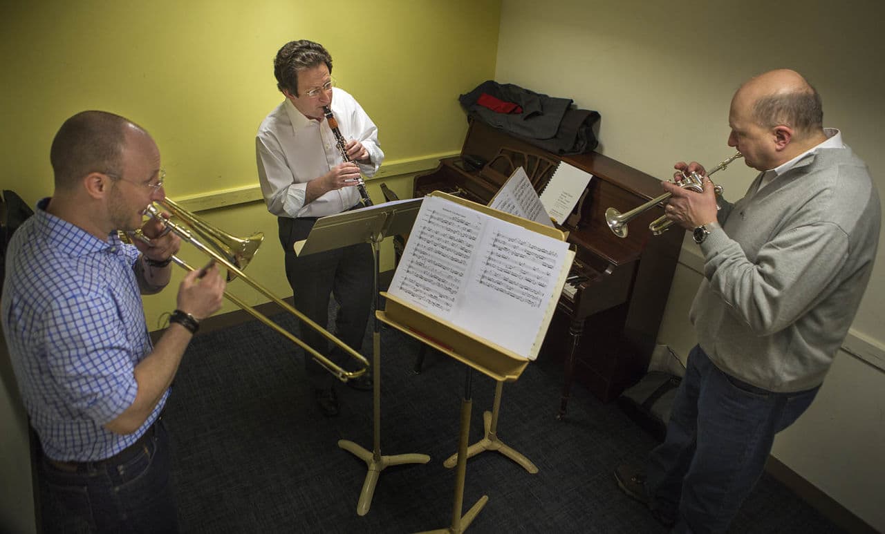Conductor Steven Lipsitt (center playing clarinet) Toby Oft (left playing trombone) and Tom Rolfs (right playing trumpet) run through arrangements in a practice space at Symphony Hall in preparation for the Bach, Beethoven &amp; Brahms Society of Boston inaugural concert on March 6. (Jesse Costa/WBUR)