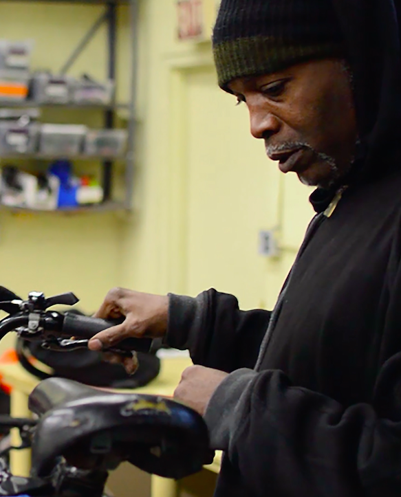 William Young, a 52-year-old Dorchester resident and avid biker, helps repair a bike at Bowdoin Bike School. (Hadley Green for WBUR)