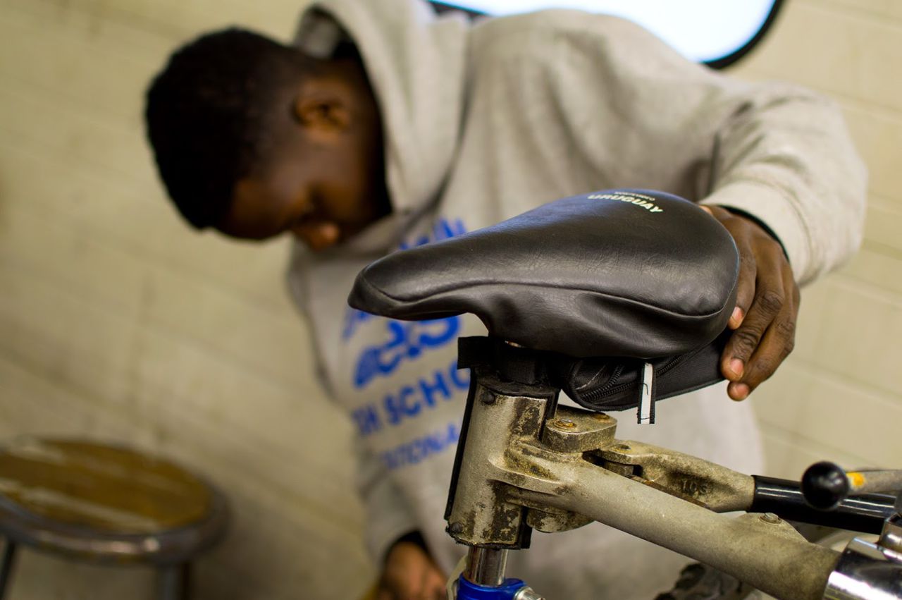 Adly Francois, a volunteer bike mechanic at Bowdoin Bike School who has been working with Noah for three years, repairs a customer’s bike. (Hadley Green for WBUR)