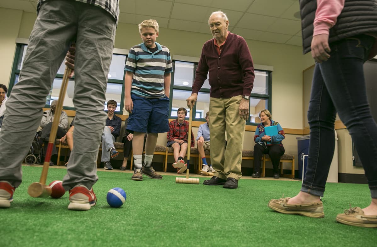Greg Kintzele, left, and Bill Taylor, right, watch as others play croquet at Graland Country Day School in Denver. (Nathaniel Minor/CPR News)