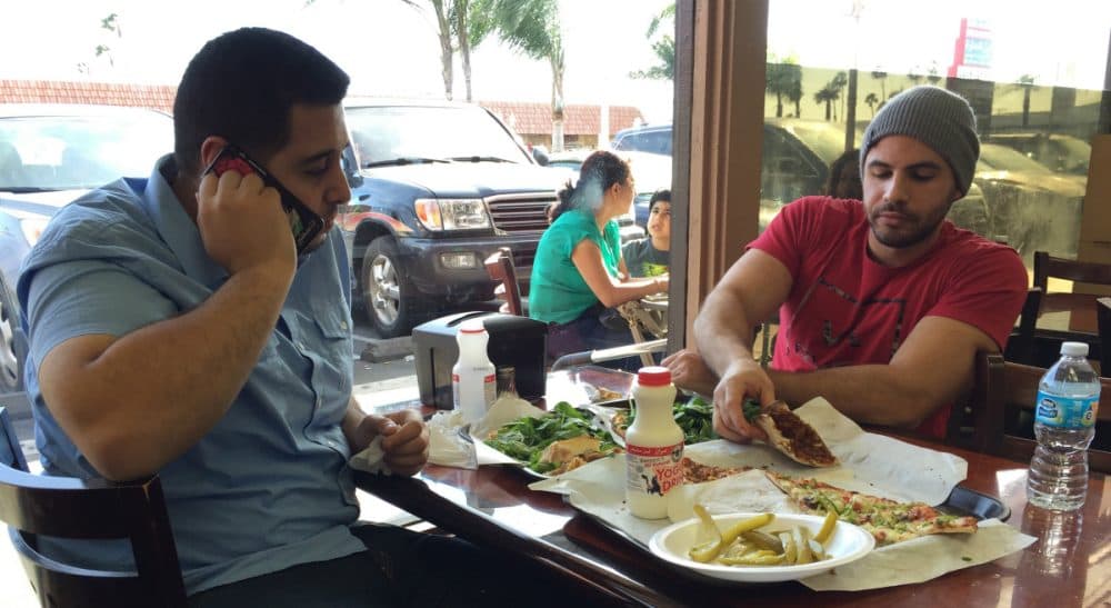 Nas Juma, 22, left, and Omar Ghanim, 23, enjoy Lebanese pizza at Forn Al Hara restaurant in Orange County's Little Arabia in Anaheim, Calif., Tuesday, March 22, 2016. Earlier that day, Republican presidential candidate Ted Cruz said that surveillance in Muslim neighborhoods in the U.S. must be intensified following the deadly bombings at Brussels. (Gillian Flaccus/AP)