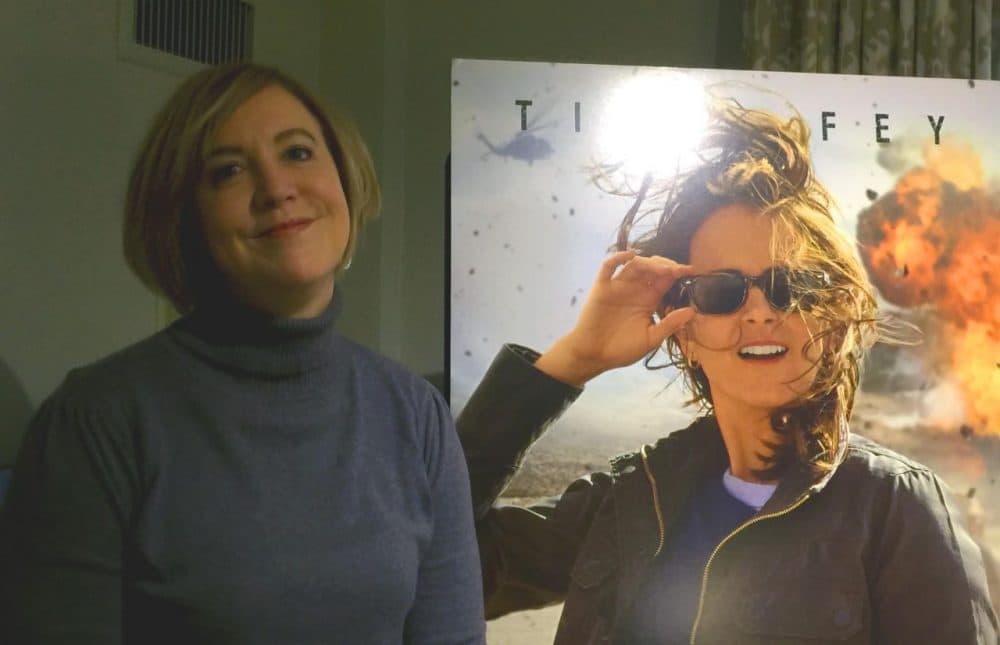 Kim Barker, posing next to a poster for the film based on her time covering the war in Afghanistan. (Charles Munitz for WBUR)