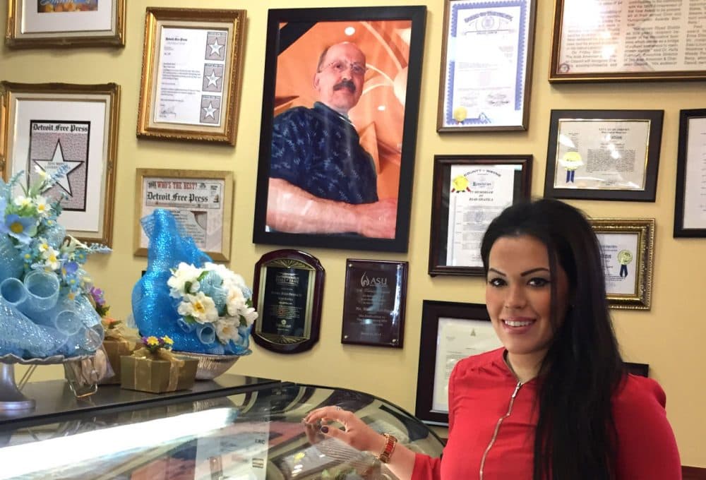 Nada Shatila, owner of Shatila Bakery & Cafe in Dearborn, Michigan, stands next to a photo of her father Riad Shatila, a Lebanese immigrant, founded it it 1979. (Robin Young/Here & Now)